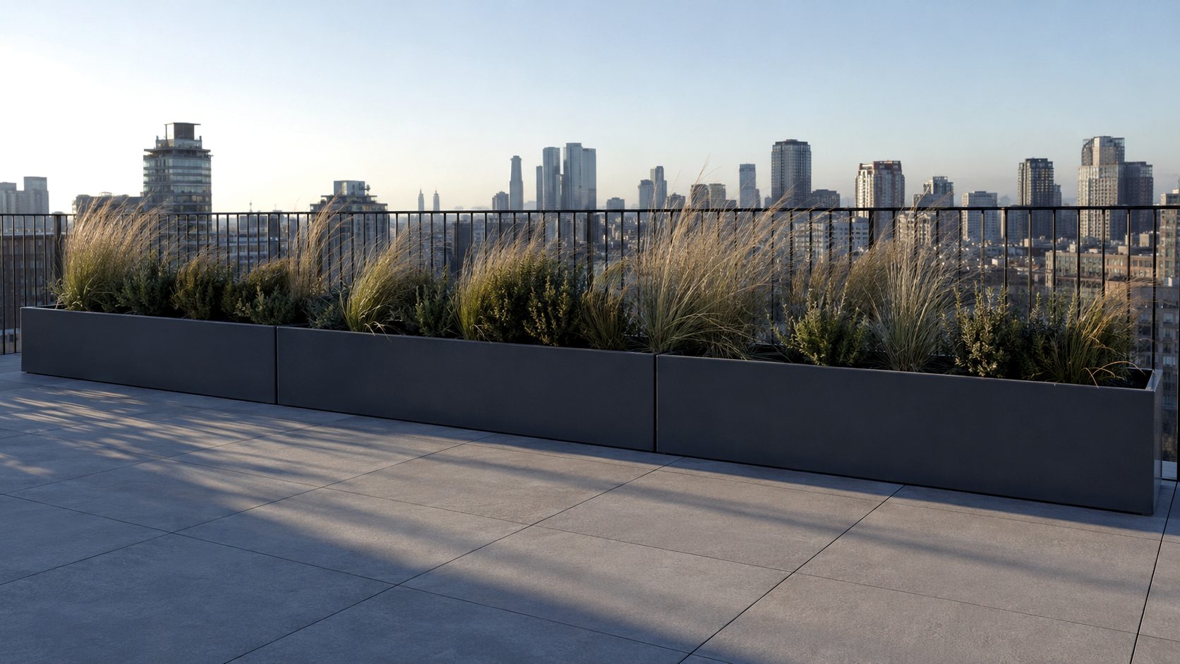Illustration of three long dark grey steel planters with ornamental grasses along the edge of a paved roof terrace