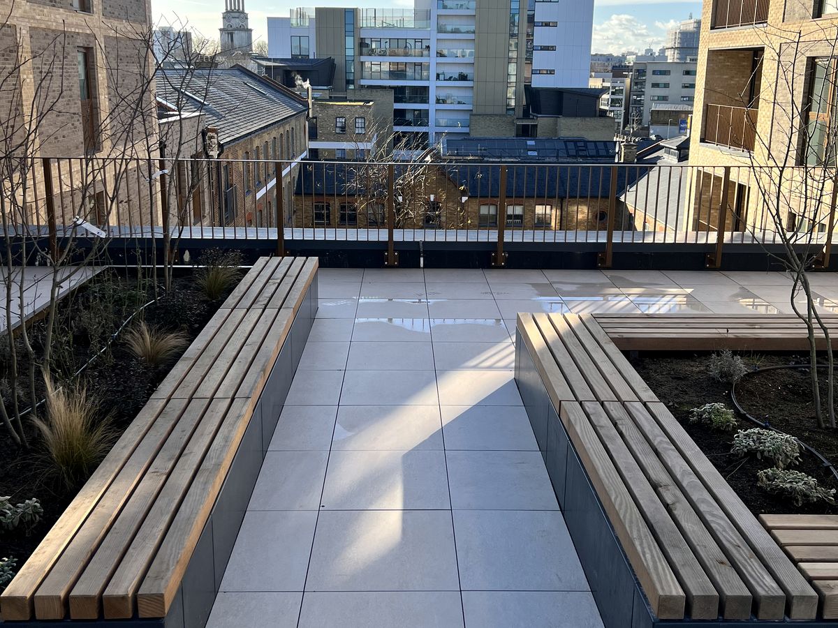 Timber bench seating integrated into steel planters on a porcelain roof terrace